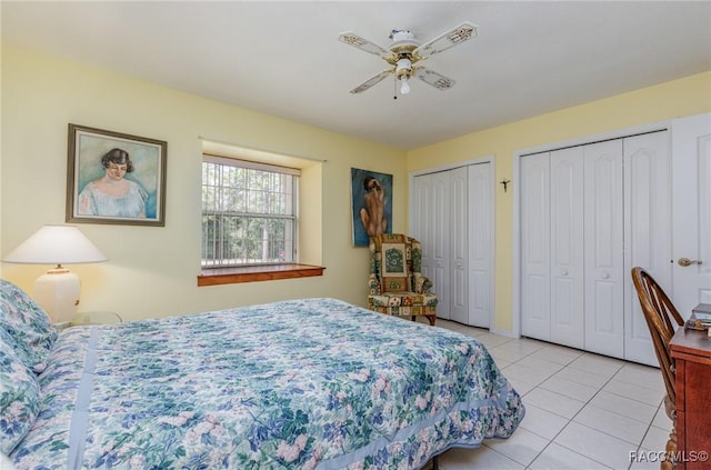 tiled bedroom featuring ceiling fan and multiple closets