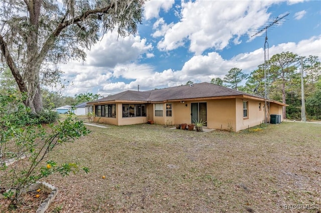 rear view of house with a yard, central AC unit, and stucco siding