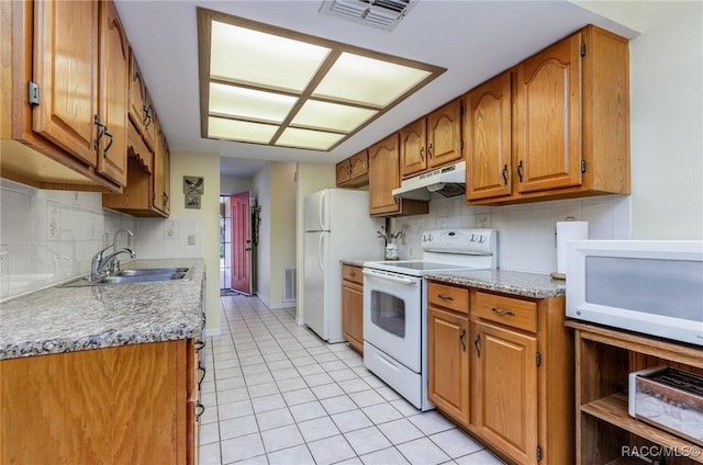 kitchen featuring light tile patterned floors, visible vents, a sink, white appliances, and under cabinet range hood