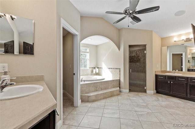 bathroom with vaulted ceiling, independent shower and bath, vanity, ceiling fan, and tile patterned floors