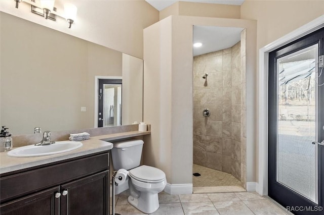 bathroom with tiled shower, vanity, toilet, and tile patterned flooring