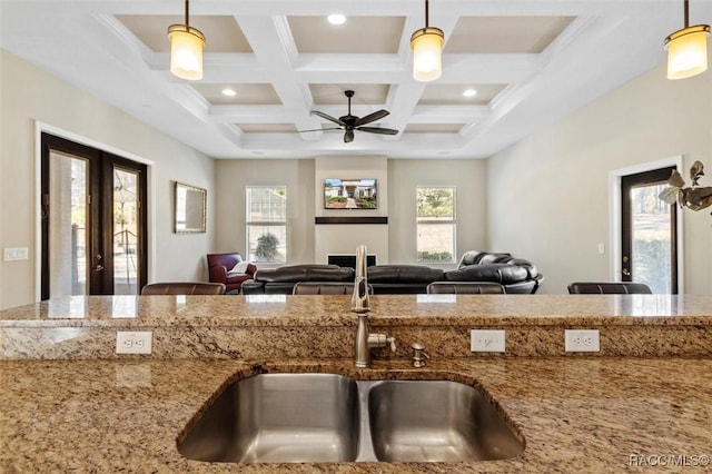 kitchen featuring pendant lighting, sink, light stone counters, a healthy amount of sunlight, and french doors