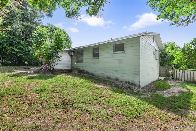 back of house featuring a lawn and a wall mounted AC