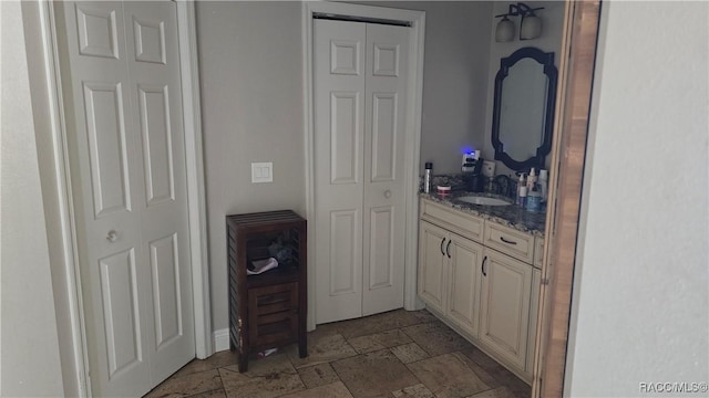 bathroom with stone tile floors, a closet, and vanity