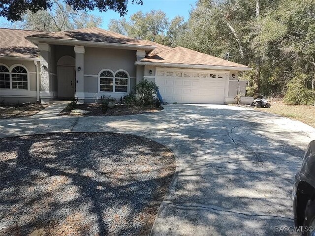 ranch-style home featuring a garage, concrete driveway, and stucco siding