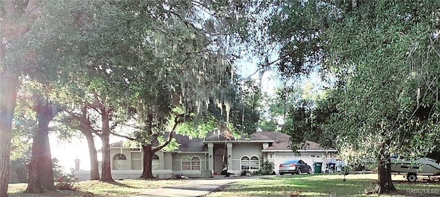 ranch-style house with a front lawn, an attached garage, and stucco siding