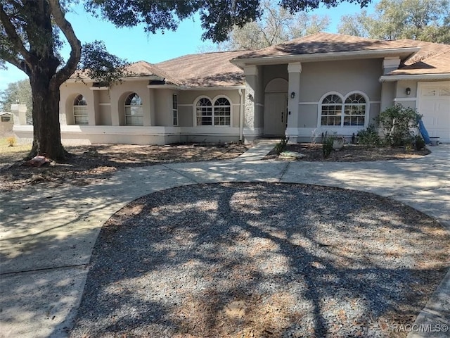 view of front facade featuring a garage, concrete driveway, and stucco siding