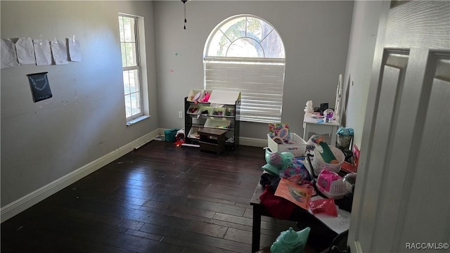 recreation room with baseboards and dark wood-style flooring