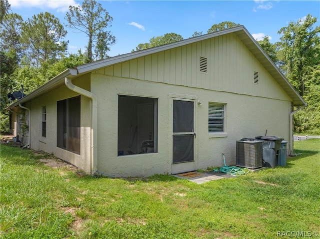 rear view of property featuring a lawn and central AC unit