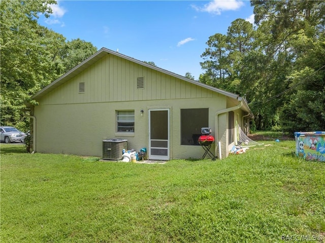 rear view of house featuring a lawn and central AC