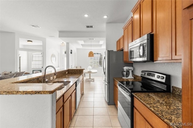12 Colubrina Ct, Homosassa, FL 34446 - kitchen featuring appliances with stainless steel finishes, a sink, brown cabinets, a kitchen island with sink, and light tile patterned floors