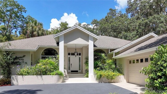 750 NW Snug Harbor Rd, Crystal River, FL 34428 - view of front of house with a shingled roof, stucco siding, an attached garage, and driveway