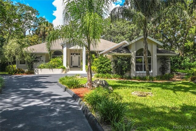 750 NW Snug Harbor Rd, Crystal River, FL 34428 - view of front facade featuring stucco siding, a front yard, and asphalt driveway