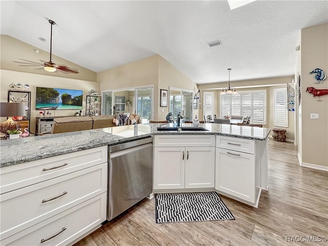 kitchen with white cabinets, light stone countertops, vaulted ceiling, stainless steel dishwasher, and a sink