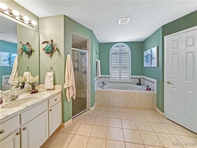 bathroom featuring a garden tub, a stall shower, vanity, a textured ceiling, and tile patterned flooring