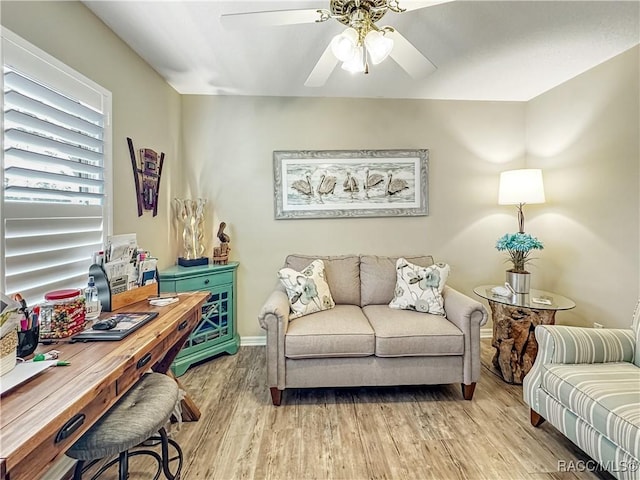 living area with light wood-style floors, ceiling fan, and baseboards