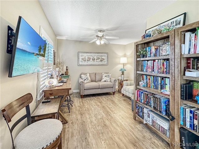 sitting room featuring ceiling fan, a textured ceiling, baseboards, and wood finished floors