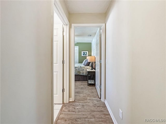 hall featuring light wood-type flooring and baseboards