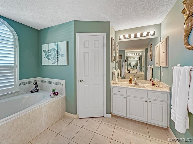 bathroom featuring vanity, a textured ceiling, tile patterned flooring, baseboards, and a bath