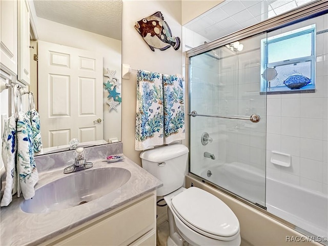 bathroom featuring toilet, bath / shower combo with glass door, and vanity