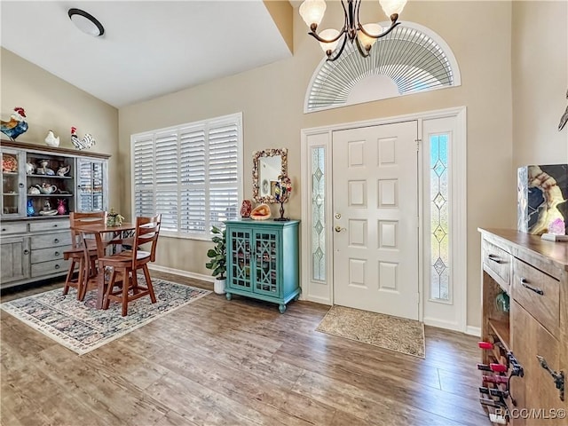 foyer entrance with a notable chandelier, baseboards, and wood finished floors