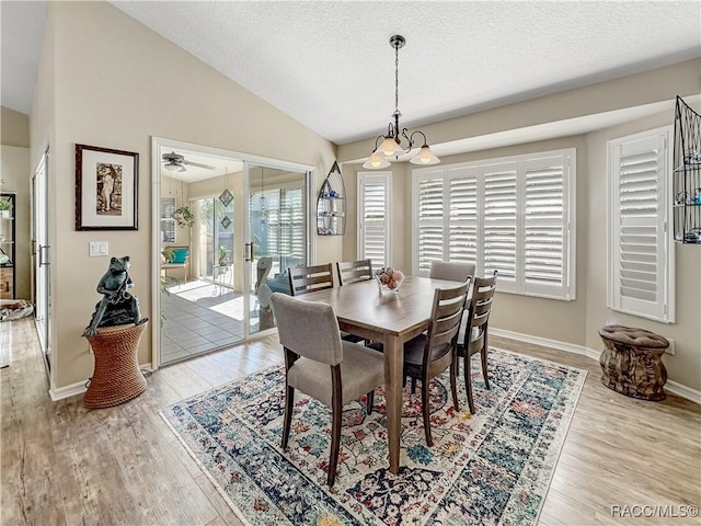 dining room featuring baseboards, lofted ceiling, wood finished floors, an inviting chandelier, and a textured ceiling