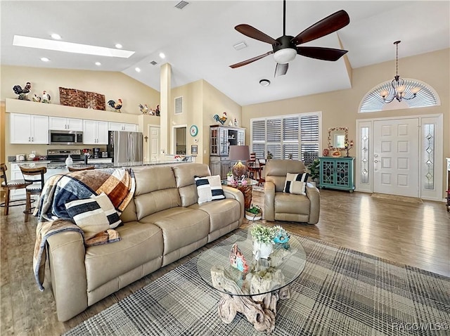 living area featuring recessed lighting, high vaulted ceiling, wood finished floors, and ceiling fan with notable chandelier