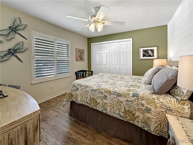 bedroom with a closet, a textured ceiling, baseboards, and wood finished floors