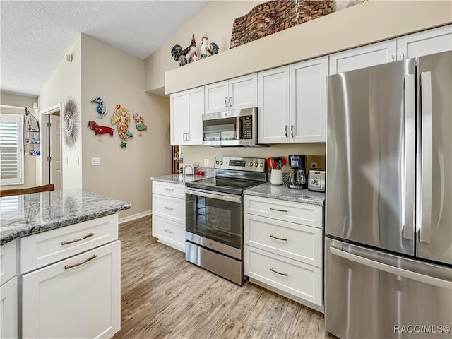 kitchen with a textured ceiling, light wood-style flooring, stainless steel appliances, white cabinetry, and light stone countertops