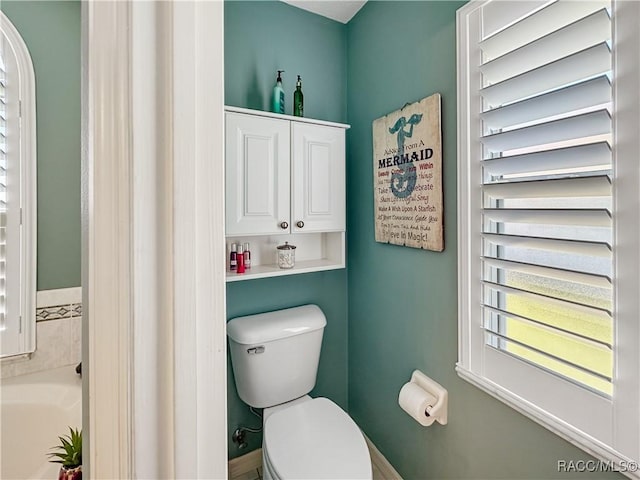 bathroom featuring toilet and a tub to relax in