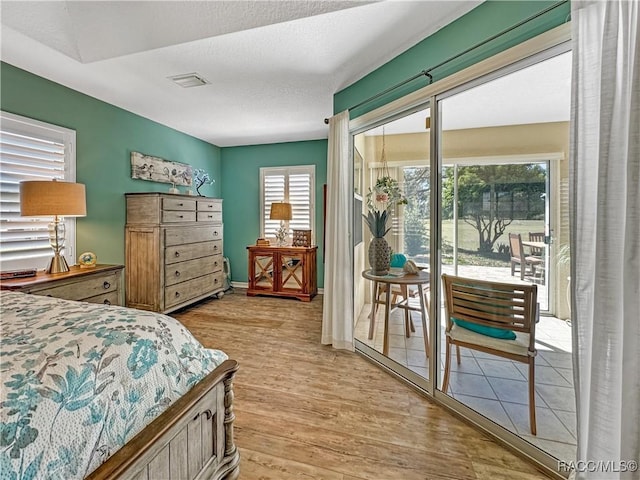 bedroom featuring access to outside, light wood-style flooring, visible vents, and baseboards