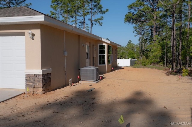 7792 N Susan Ave, Dunnellon, FL 34433 - view of home's exterior with stucco siding, cooling unit, fence, roof with shingles, and stone siding