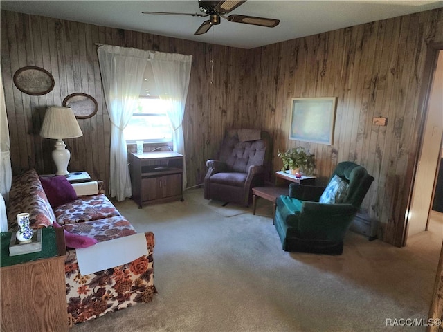 living room featuring ceiling fan, wood walls, and light colored carpet