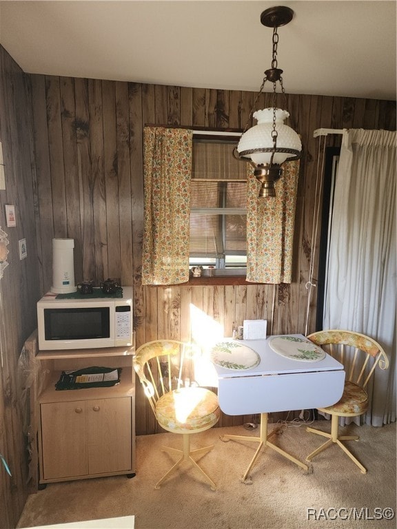 dining space featuring carpet and wooden walls