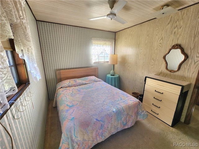 carpeted bedroom with ceiling fan and wood walls