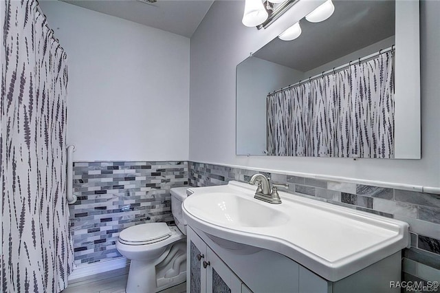 1309 Longboat Pt, Inverness, FL 34450 - full bathroom featuring toilet, vanity, a wainscoted wall, and tile walls