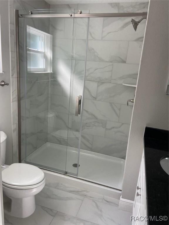 bathroom featuring vanity, a shower with shower door, and toilet