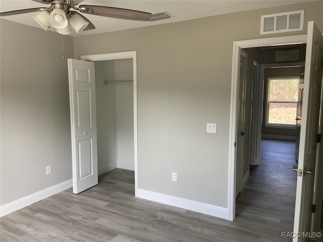 unfurnished bedroom with ceiling fan, light wood-type flooring, and a closet