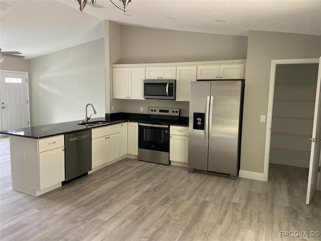 kitchen featuring vaulted ceiling, white cabinetry, sink, kitchen peninsula, and stainless steel appliances