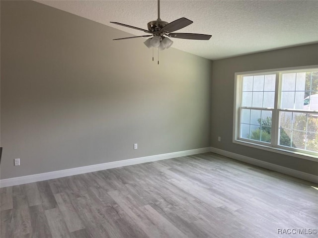 unfurnished room featuring ceiling fan, a wealth of natural light, a textured ceiling, and light hardwood / wood-style floors