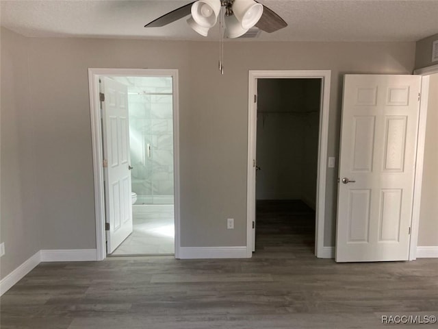 unfurnished bedroom featuring dark hardwood / wood-style floors, connected bathroom, a spacious closet, and a closet