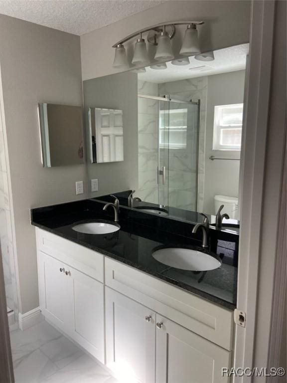 bathroom with vanity, toilet, a textured ceiling, and walk in shower