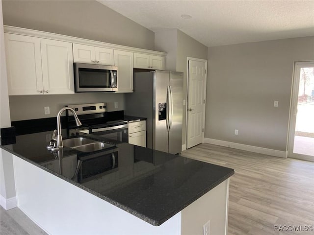 kitchen with lofted ceiling, appliances with stainless steel finishes, white cabinets, and kitchen peninsula