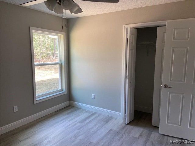 unfurnished bedroom with ceiling fan, light hardwood / wood-style flooring, a closet, and a textured ceiling