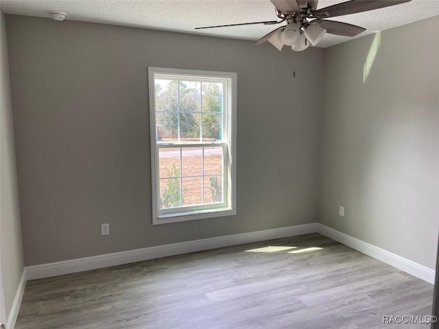 empty room featuring ceiling fan, light hardwood / wood-style floors, and a textured ceiling