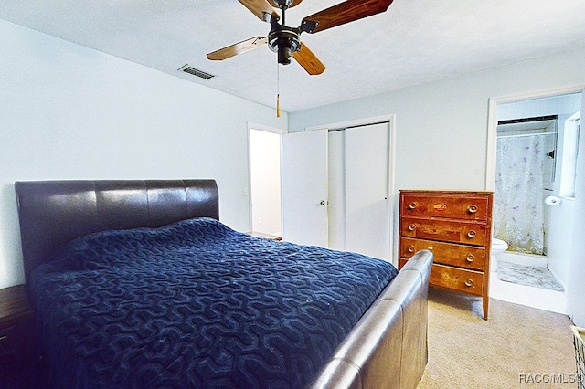 bedroom featuring ceiling fan, a closet, light colored carpet, and ensuite bath