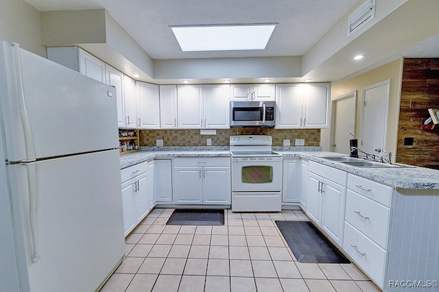 kitchen featuring decorative backsplash, kitchen peninsula, white appliances, wooden walls, and white cabinets