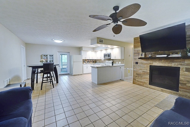 kitchen featuring tasteful backsplash, kitchen peninsula, a textured ceiling, white appliances, and white cabinets