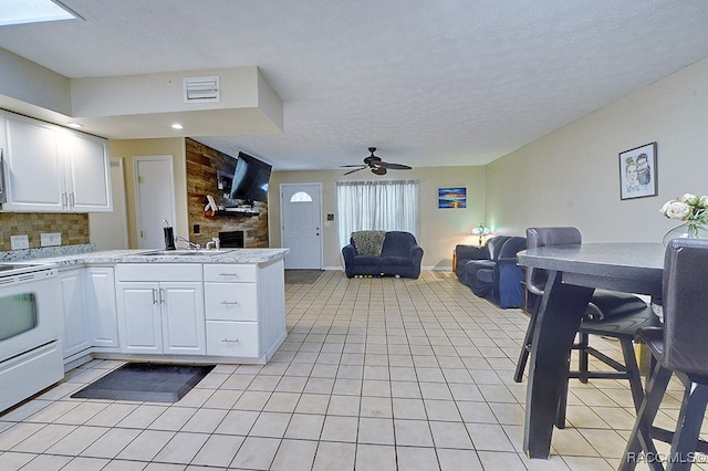 kitchen featuring kitchen peninsula, white range oven, ceiling fan, sink, and white cabinets