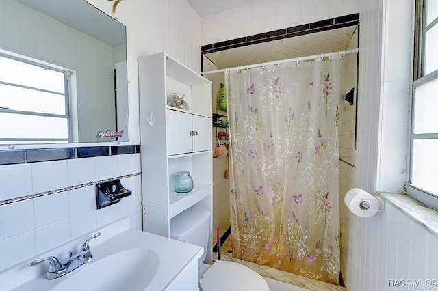 bathroom with a shower with curtain, toilet, tile walls, and sink